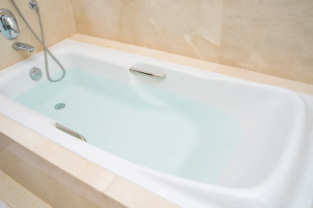 White bathtub holding standing water below a handheld shower head