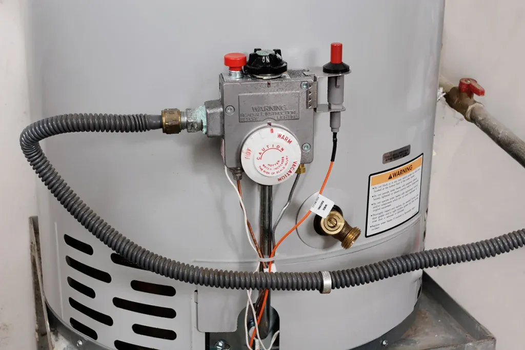 Gas control valve and thermostat dial on the front of a tank water heater