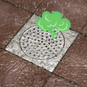 Square shower drain cover on a tiled floor with a green cartoon cloud rising from it to show a bad smell