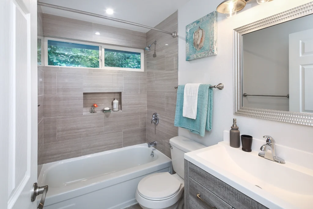 Bathroom with a tiled tub surround, a toilet and a vanity sink