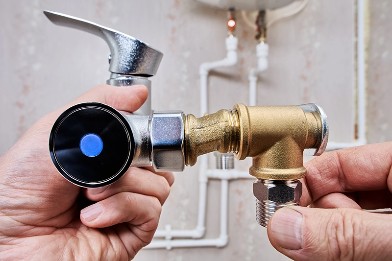 Hands holding a brass reducer fitting threaded onto a chrome valve