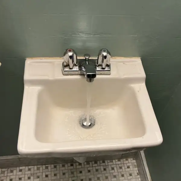 After: The same bathroom sink with water running clear down the cleared drain.