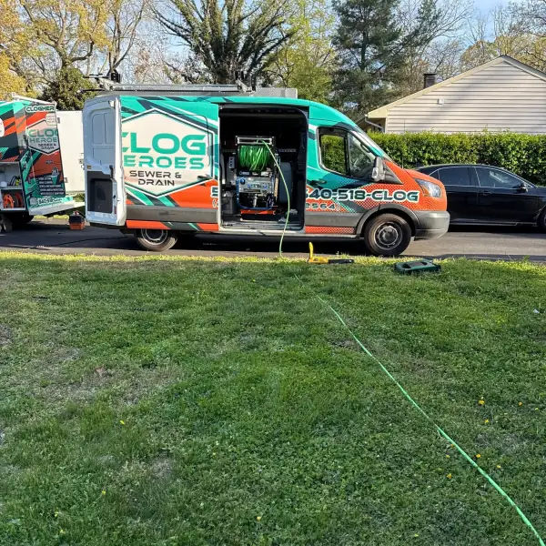 Clog Heroes van on a residential street with a jetter hose run across the lawn.