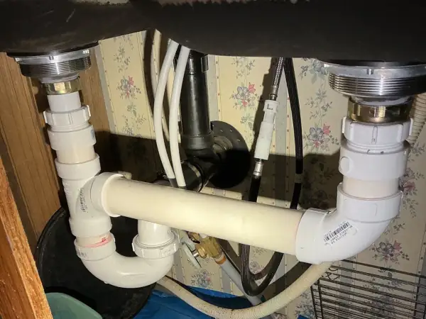 After: New white PVC drain lines installed under the kitchen double sink.