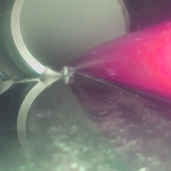 Sewer camera view of the jetter cutting roots at a pipe fitting.