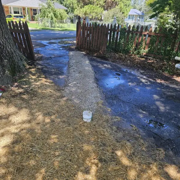 Backfilled and strawed sewer trench running out to the street.