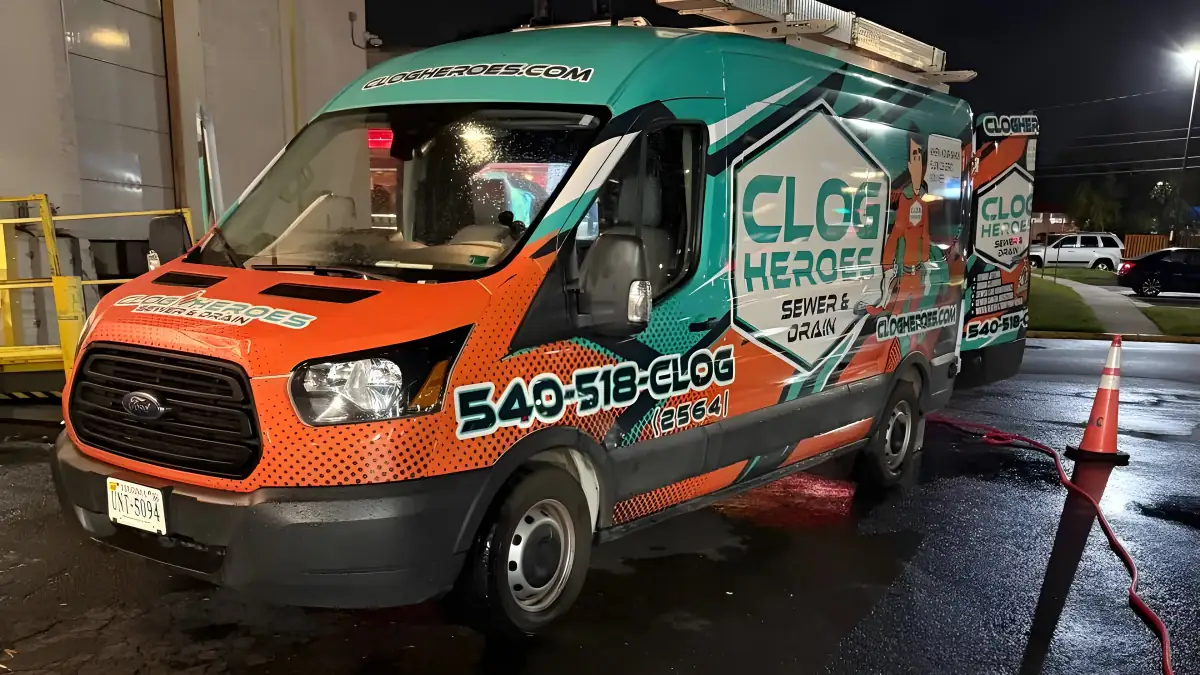 Clog Heroes van parked at night under a streetlight with cones and hose out.