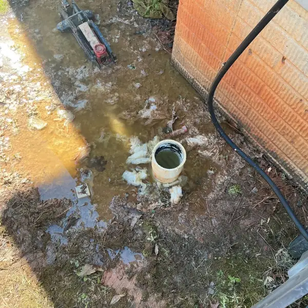 Before: Outdoor sewer cleanout overflowing with sewage pooled around it.