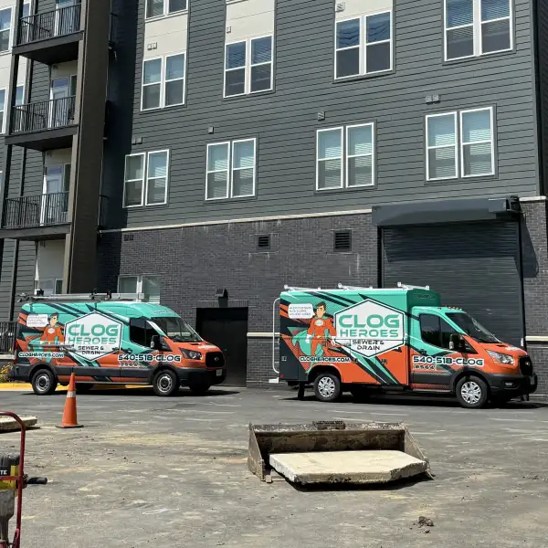 Two Clog Heroes service vehicles parked behind a new apartment building during a commercial hydro jetting job.