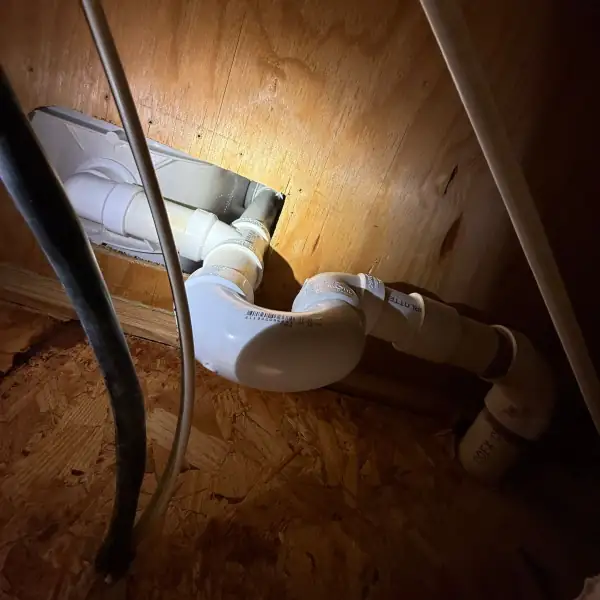 New PVC tub drain piping installed through the access panel behind the tub.