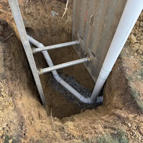 Deep sewer trench shored with braces beside the house foundation.