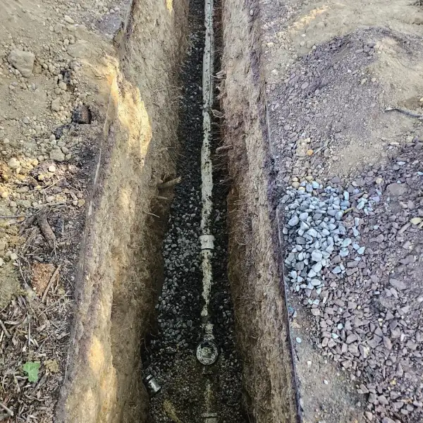 Long straight trench with the new sewer pipe bedded in the bottom.
