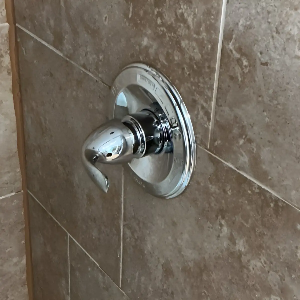 New shower valve trim installed on the tiled wall.