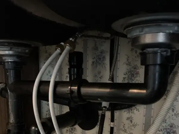 Before: Old black drain lines leaking under a kitchen double sink.
