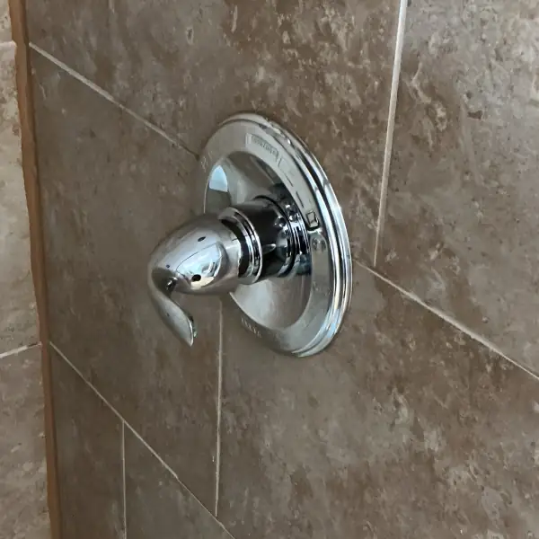After: New shower valve trim installed on the tiled wall.